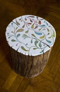 a piece of wood that has been painted with different colors and designs on it, sitting on a wooden floor