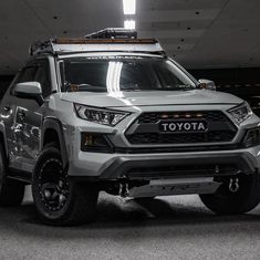 the front end of a white toyota truck parked in a garage with its lights on