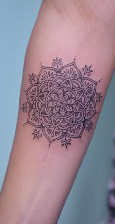 a black and white tattoo design on the right arm, with an intricate flower in the center