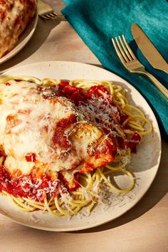 a white plate topped with pasta covered in sauce and parmesan cheese on top of it