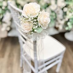 a white chair with flowers on it in front of other chairs and one is empty