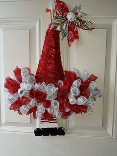 a red and white christmas wreath hanging on a door