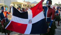 two men in costumes holding a flag and some palm fronds on the street