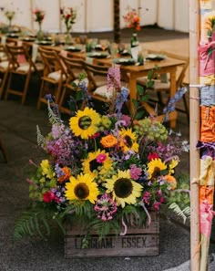 a wooden crate filled with lots of flowers on top of a floor next to tables