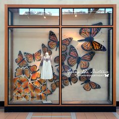 there is a display case with many butterflies in the glass and on the wall are two mannequins