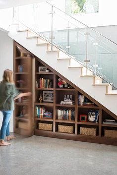 a book shelf under a stair case with books