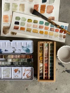 an assortment of watercolors and paints sitting on top of a table