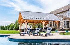 an outdoor patio with chairs and a table next to a pool in front of a house