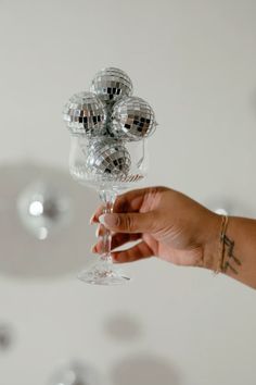 a person holding a wine glass with disco balls on it