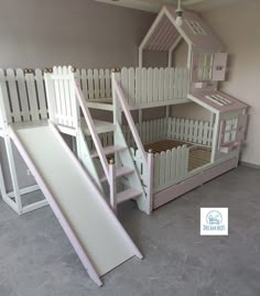 there is a pink and white bunk bed with a slide next to it on the floor