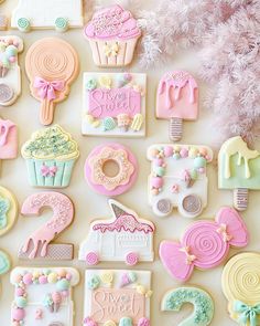 many decorated cookies are arranged on a white surface with pink and green decorations around them