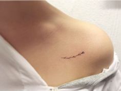 a small branch tattoo on the back of a woman's shoulder