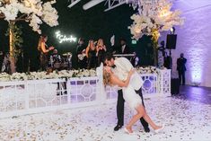 a bride and groom kissing on the dance floor at their wedding reception in front of an audience