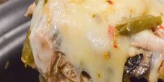 a close up of a piece of food with cheese and pickles on the side