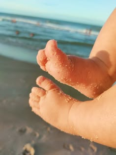 a close up of a baby's foot on the beach