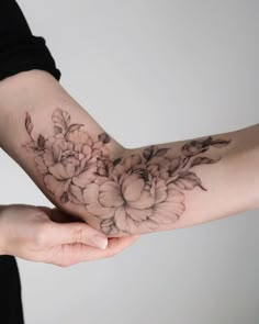 a woman holding out her arm with flowers on it