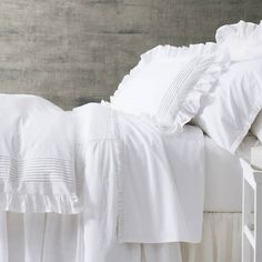 a white bed with ruffled sheets and pillows