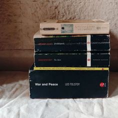 four books stacked on top of each other in front of a white sheet covered wall