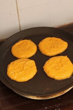 four pancakes are being cooked in a frying pan