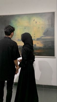 two people standing in front of a painting