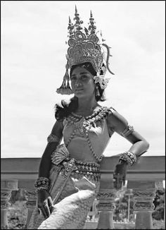 a woman dressed in an elaborate costume and headdress poses for the camera with her hands on her hips