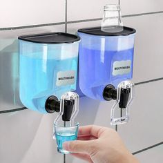 two water dispensers on the wall, one holding a glass with blue liquid