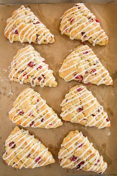 six scones with white icing on top of a baking sheet lined with parchment paper