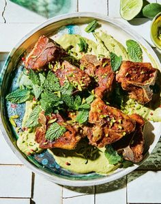 a plate filled with meat and guacamole on top of a tiled table