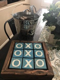 a wooden tic - tac - toe game sitting on top of a table next to a potted plant