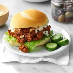 a sloppy joe sandwich on a plate with cucumbers