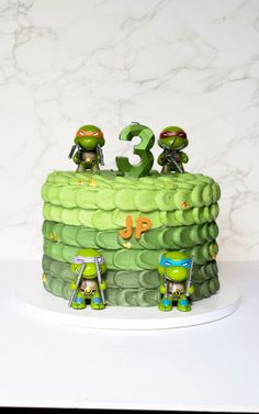 there is a green cake with two teenage mutant figures on it and the number 3