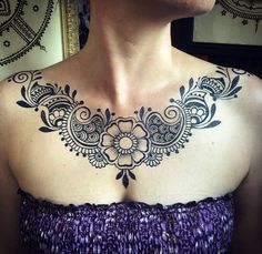 a woman wearing a purple dress has a black and white tattoo design on her chest