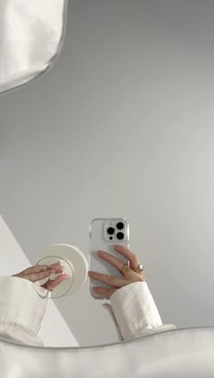 a woman in white is holding her cell phone up to the camera while wearing a hat