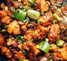 a pan filled with chicken and vegetables on top of a table next to a fork