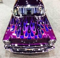 a purple and black car with flames on it's hood at an auto show