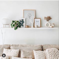 a living room filled with lots of furniture and pictures on top of a shelf above a couch