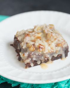 a piece of cake sitting on top of a white plate with frosting and nuts