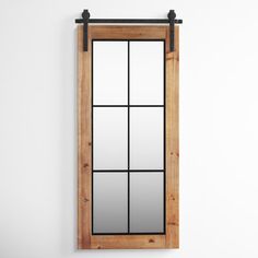 a mirror hanging on the side of a white wall next to a wooden window sill