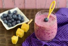 a smoothie with blueberries and pineapple on the side