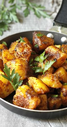 a pan filled with fried potatoes covered in herbs