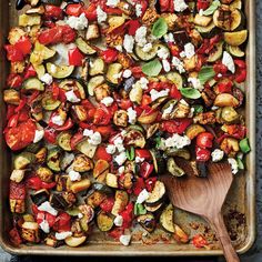 a baking pan filled with roasted vegetables and feta cheese