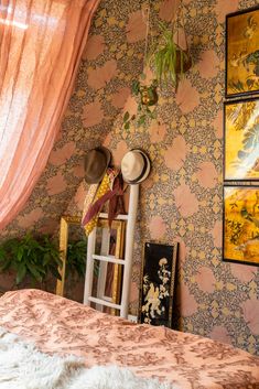 a bedroom with wallpaper and pictures on the walls, including a ladder in the corner