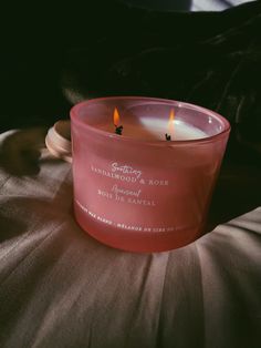 a pink candle sitting on top of a bed