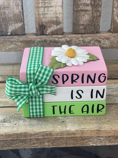 a pink box with green and white ribbon on it that says spring is in the air