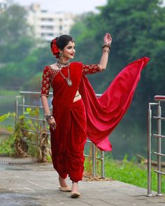 a woman in a red sari is walking down the street with her arms outstretched