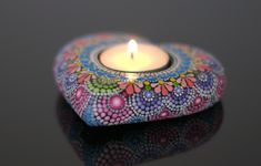 a lit candle sitting on top of a table next to a black surface with flowers painted on it