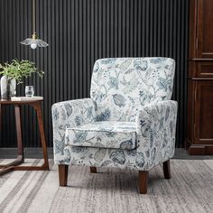 a living room with a chair, table and plant on the floor in front of a black wall