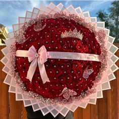 a large red rose wreath with a ribbon on it