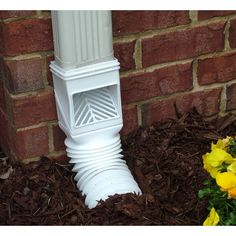 a close up of a white pipe on the ground next to some flowers and dirt