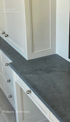 a kitchen with white cabinets and gray counter tops